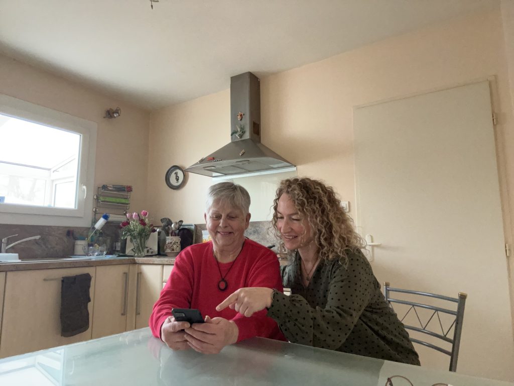 Personne agée avec une personne lui expliquant le fonctionnement de son téléphone portable.